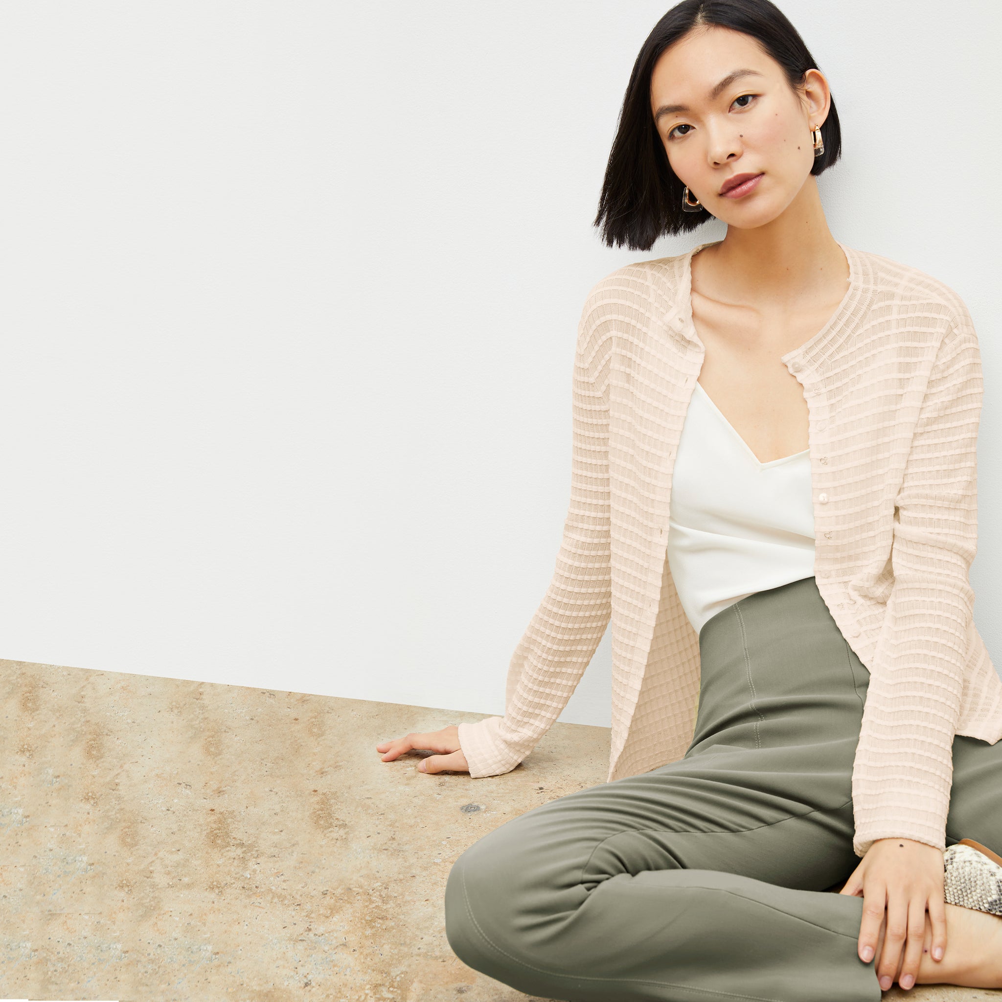 Front image of a woman sitting wearing the Emerson Cardigan in Meringue