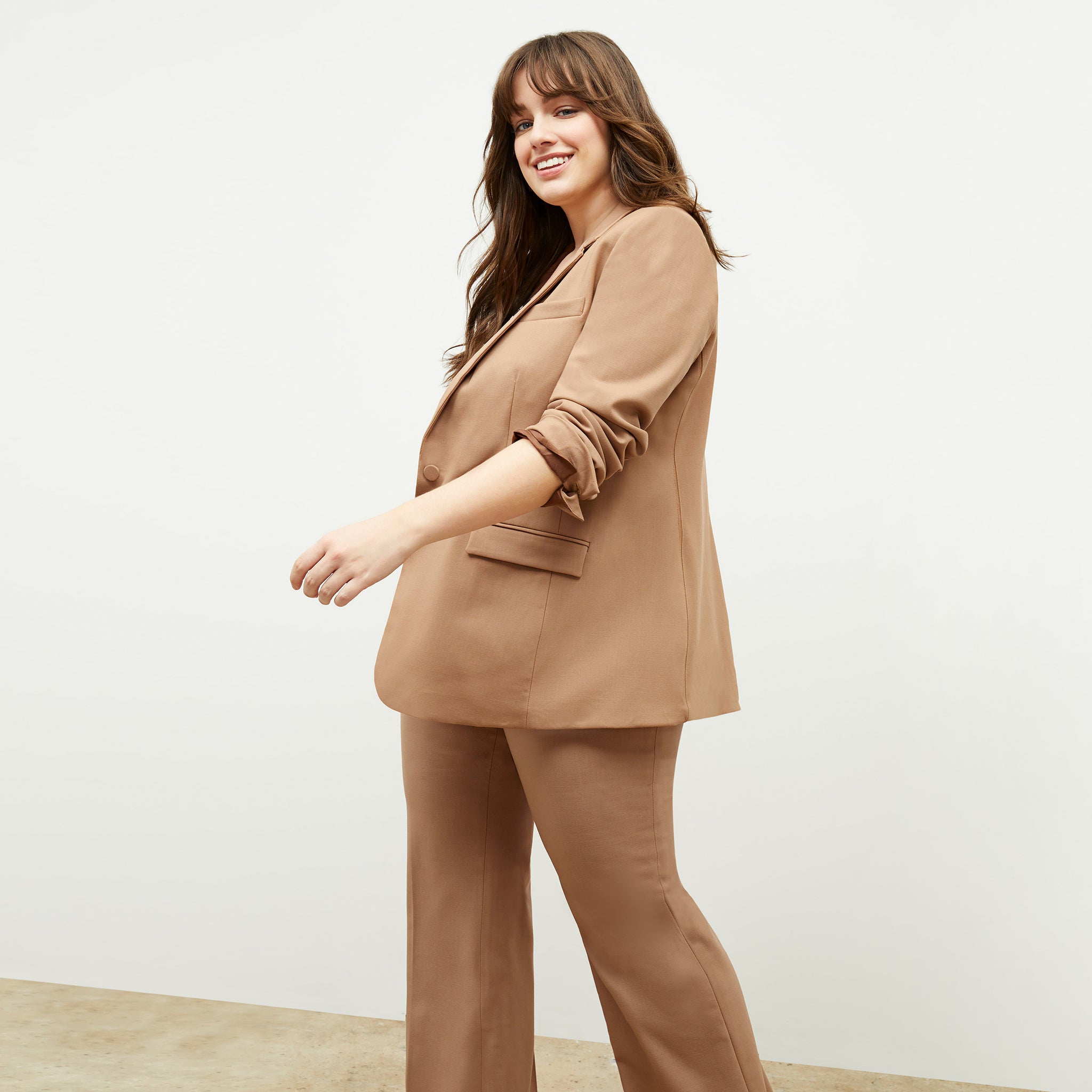 Front image of a woman standing wearing the Yiyan Blazer in Camel