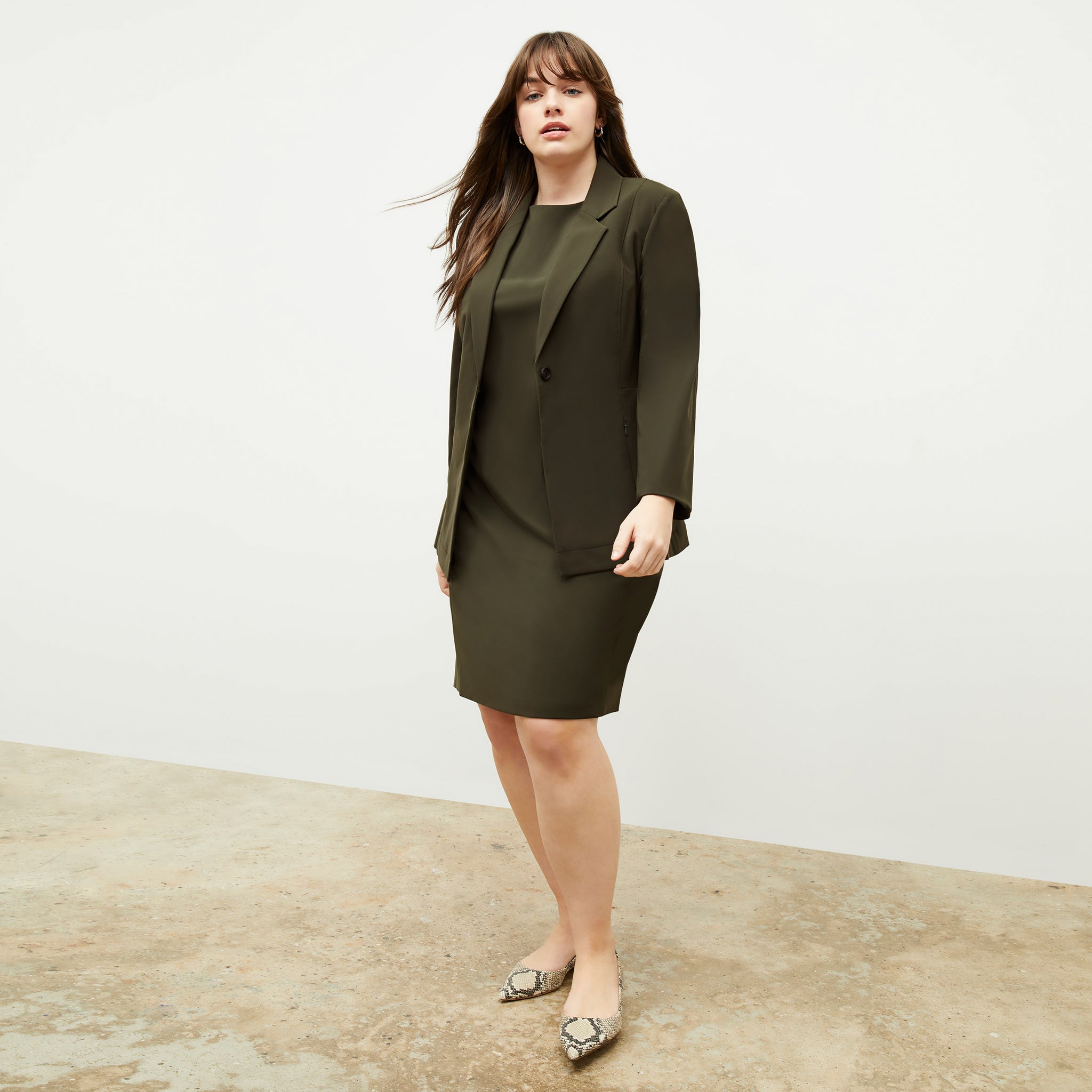 Front image of a woman standing wearing the Maaza Dress—Origami Suiting in Olive