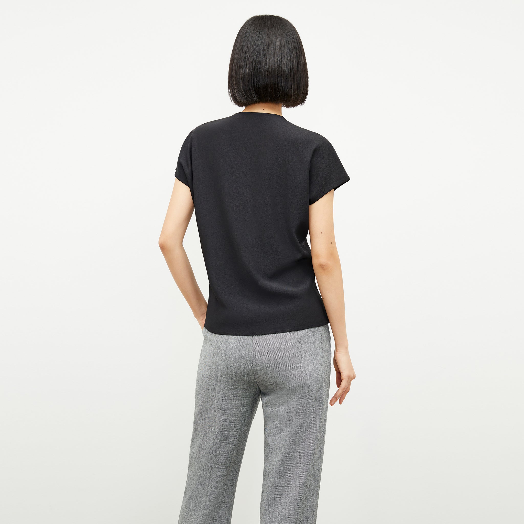 Back image of a woman standing wearing the antonia top soft wave in black