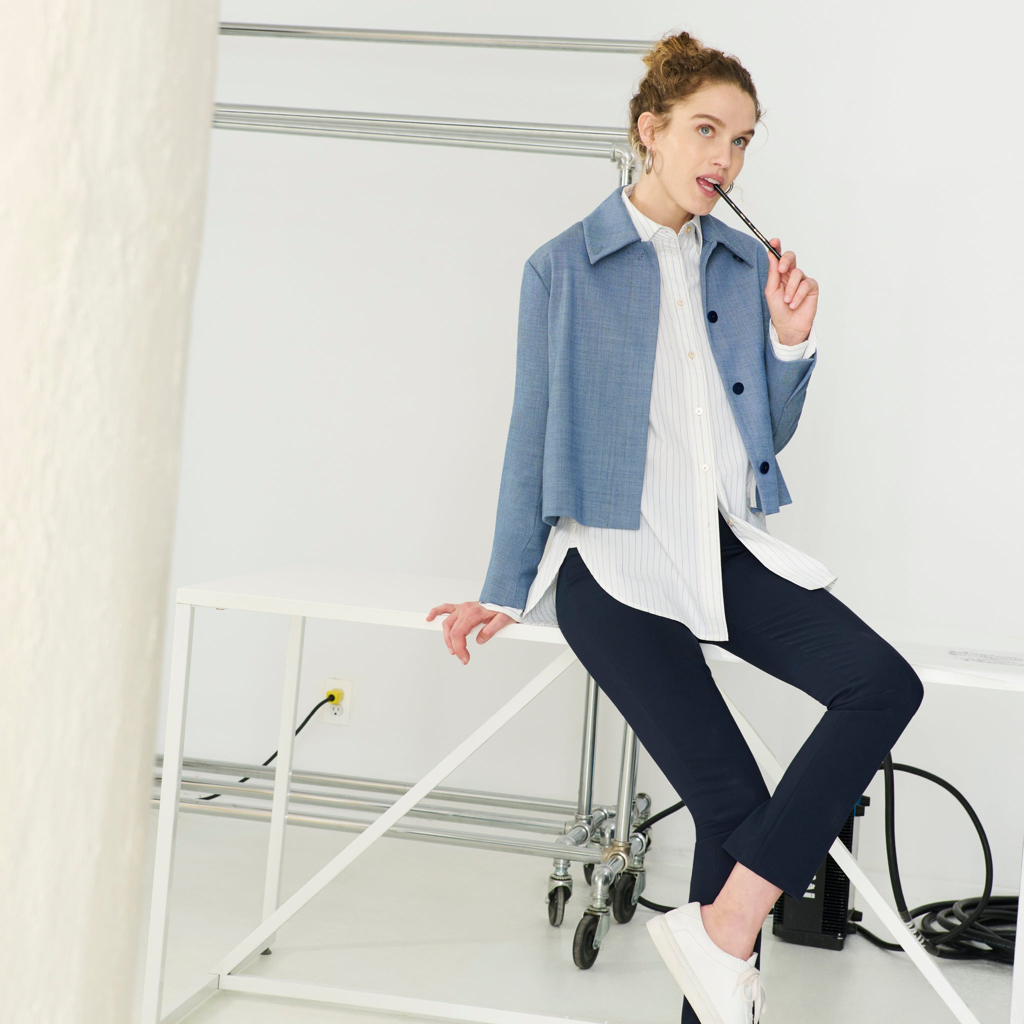 Image of a woman sitting on a table in the Nicky Jacket in Indigo and White