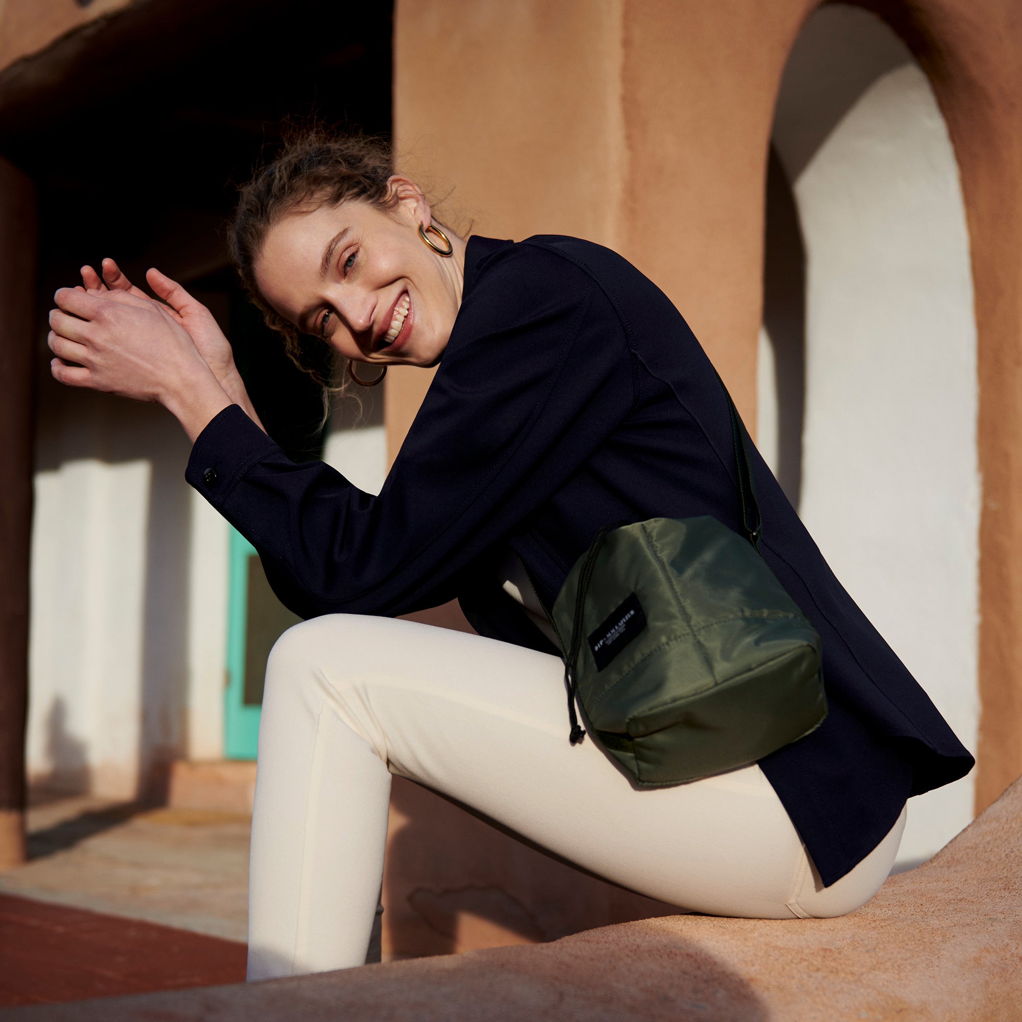 Front image of a woman wearing the Bags in Progress x MM Padded Mini Bucket Bag in Khaki Green