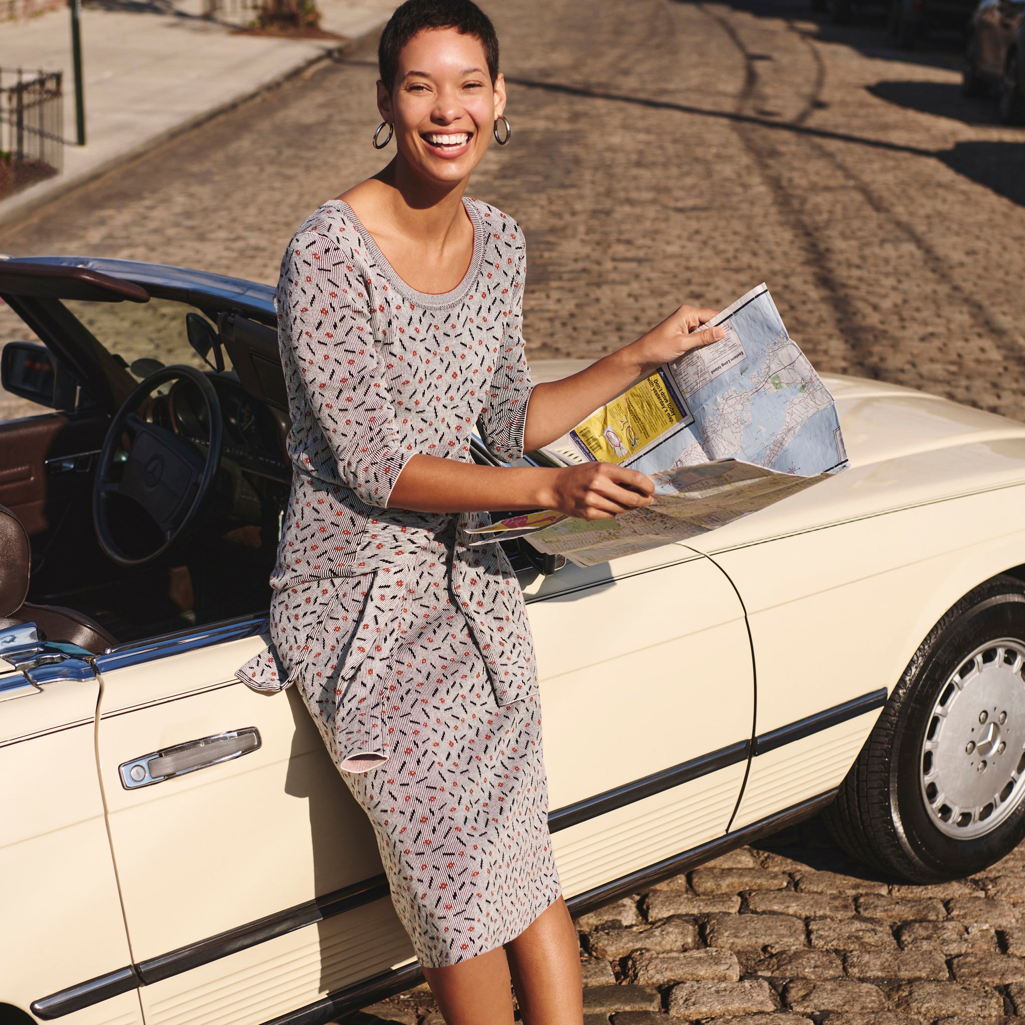 Front image of a woman leaning against a car wearing the Tippy Dress in Brick and Black