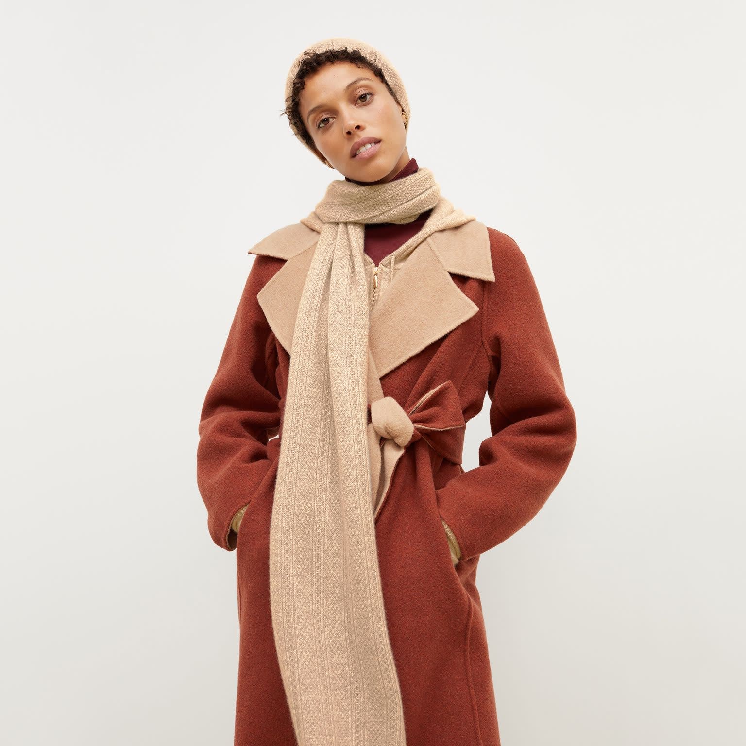Front image of a woman standing wearing the Circle Cable Scarf—Cashmere in Light Camel