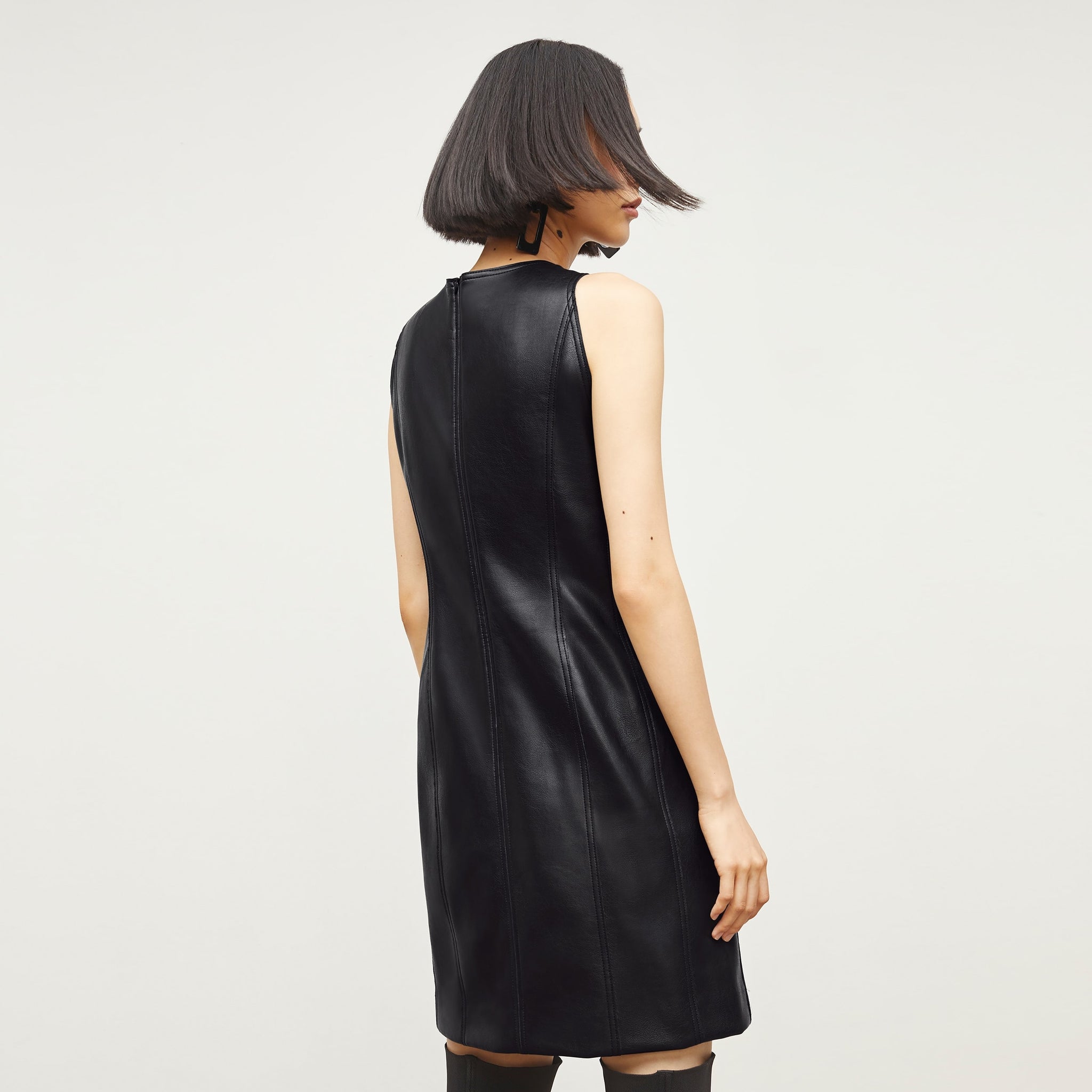 Back image of a woman standing wearing the Chloe Dress—Vegan Leather in Black