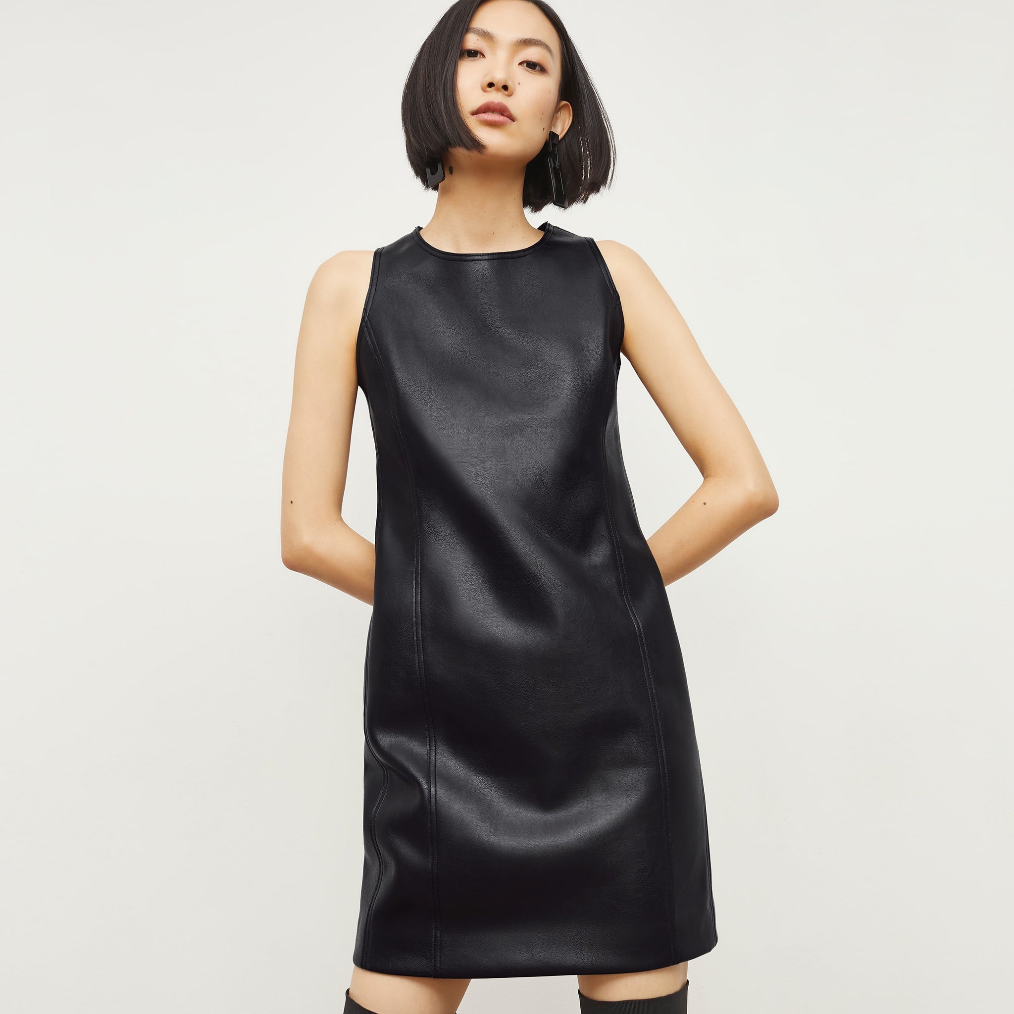 Front image of a woman standing wearing the Chloe Dress—Vegan Leather in Black