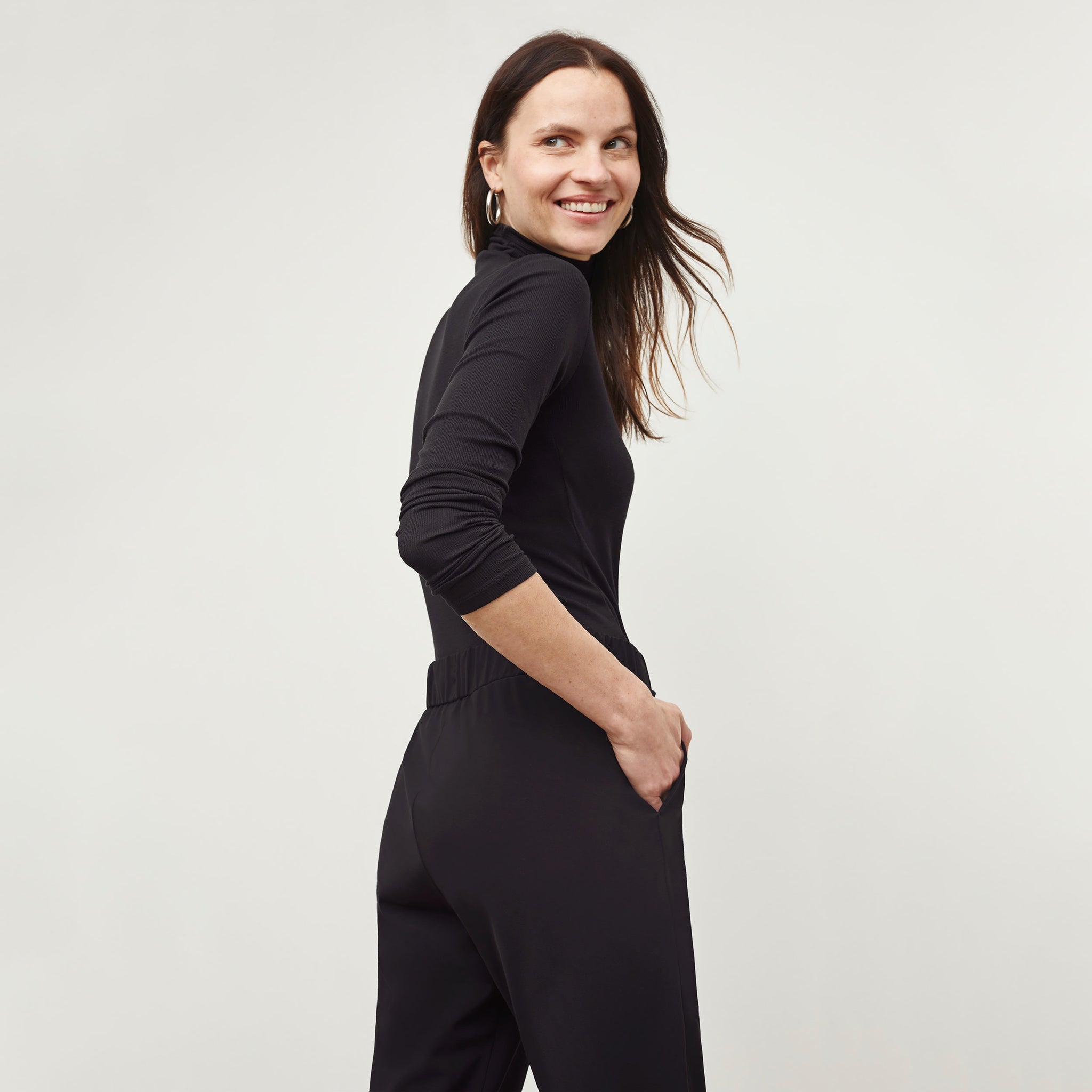 Back image of a woman standing wearing the Delaney Jogger—OrigamiTech in Black