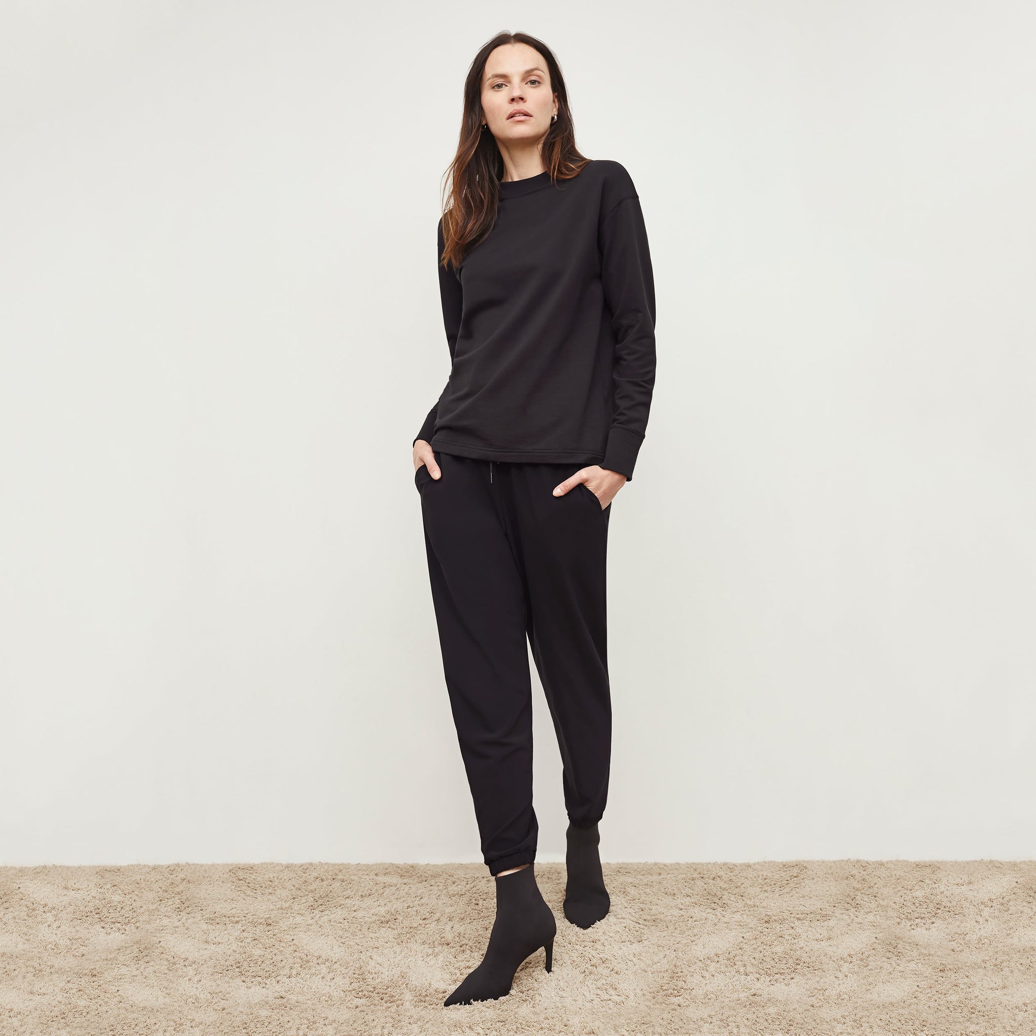 Front image of a woman standing wearing the Delaney Jogger—OrigamiTech in Black
