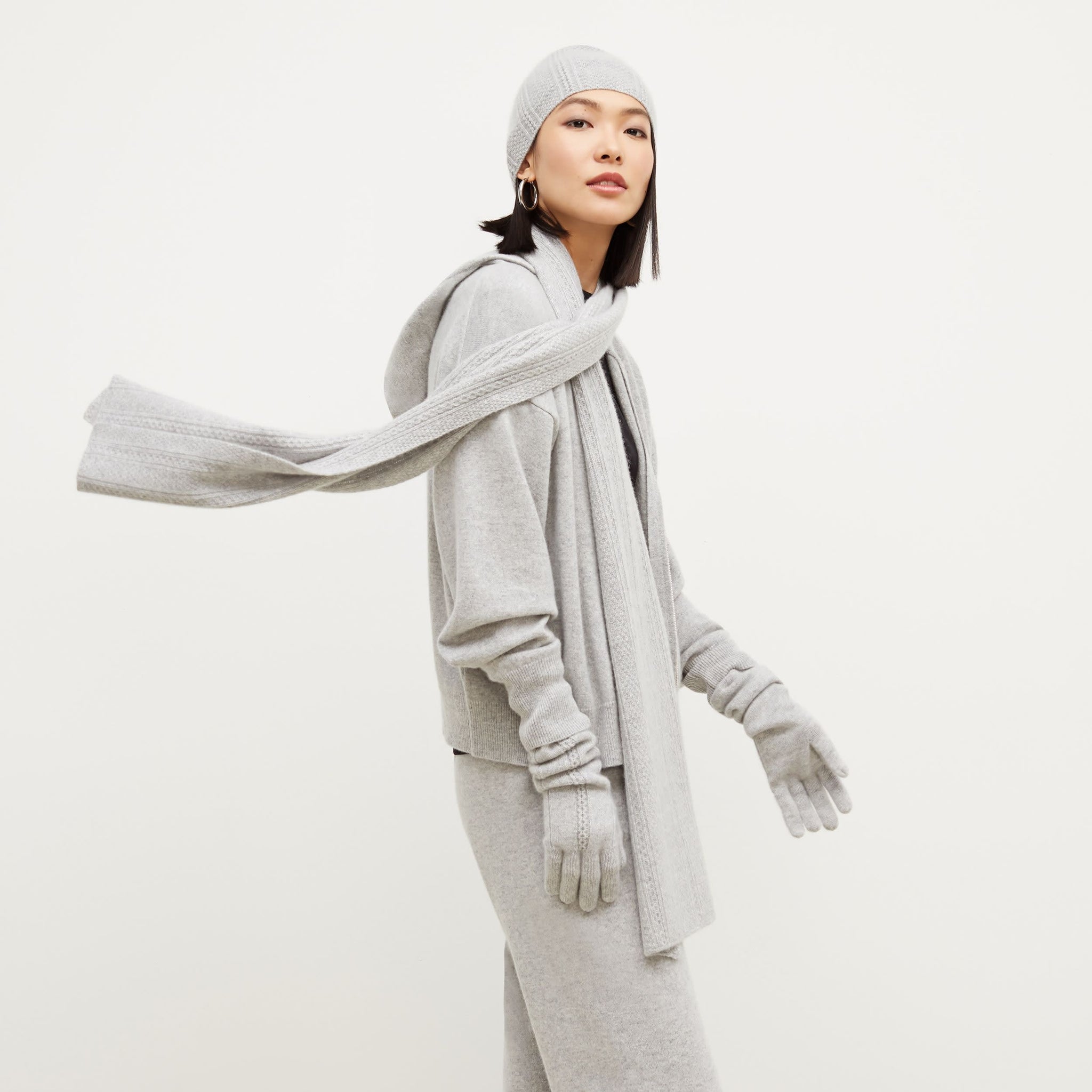 Side image of a woman standing wearing the Circle Cable Gloves—Cashmere in Heather Gray