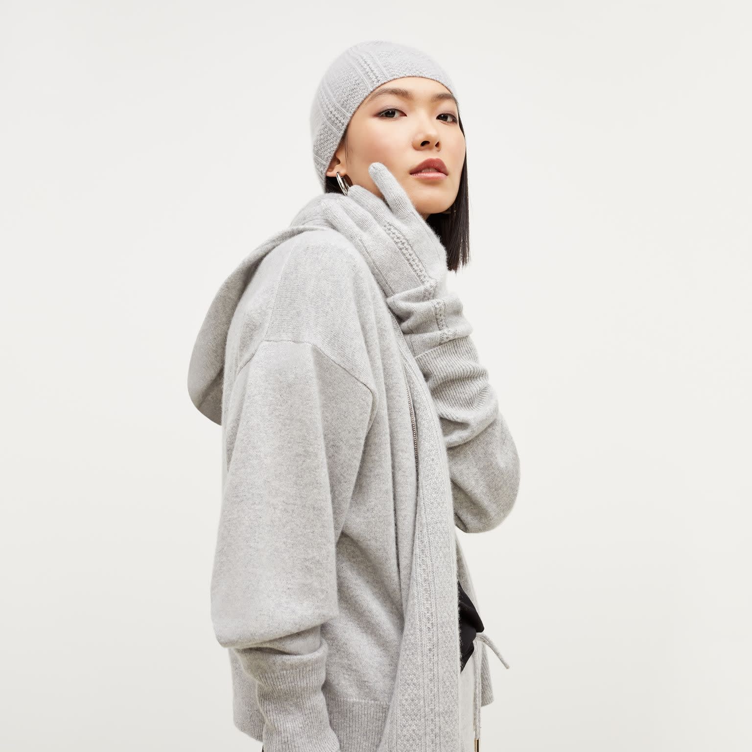 Side image of a woman standing wearing the Circle Cable Gloves—Cashmere in Heather Gray