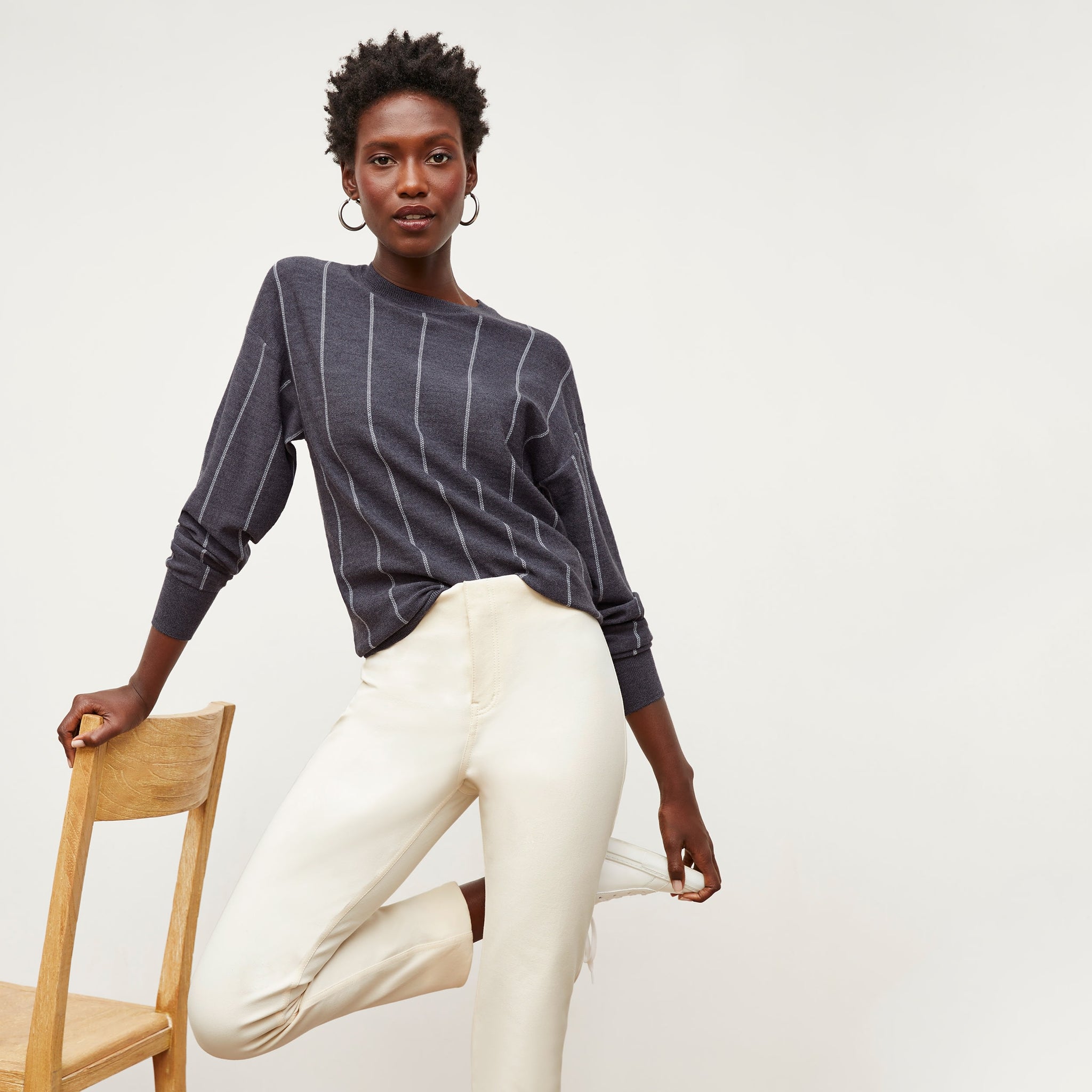 Front image of a woman standing wearing the Ingola Sweater—Braided Stripe in Charcoal / Ivory