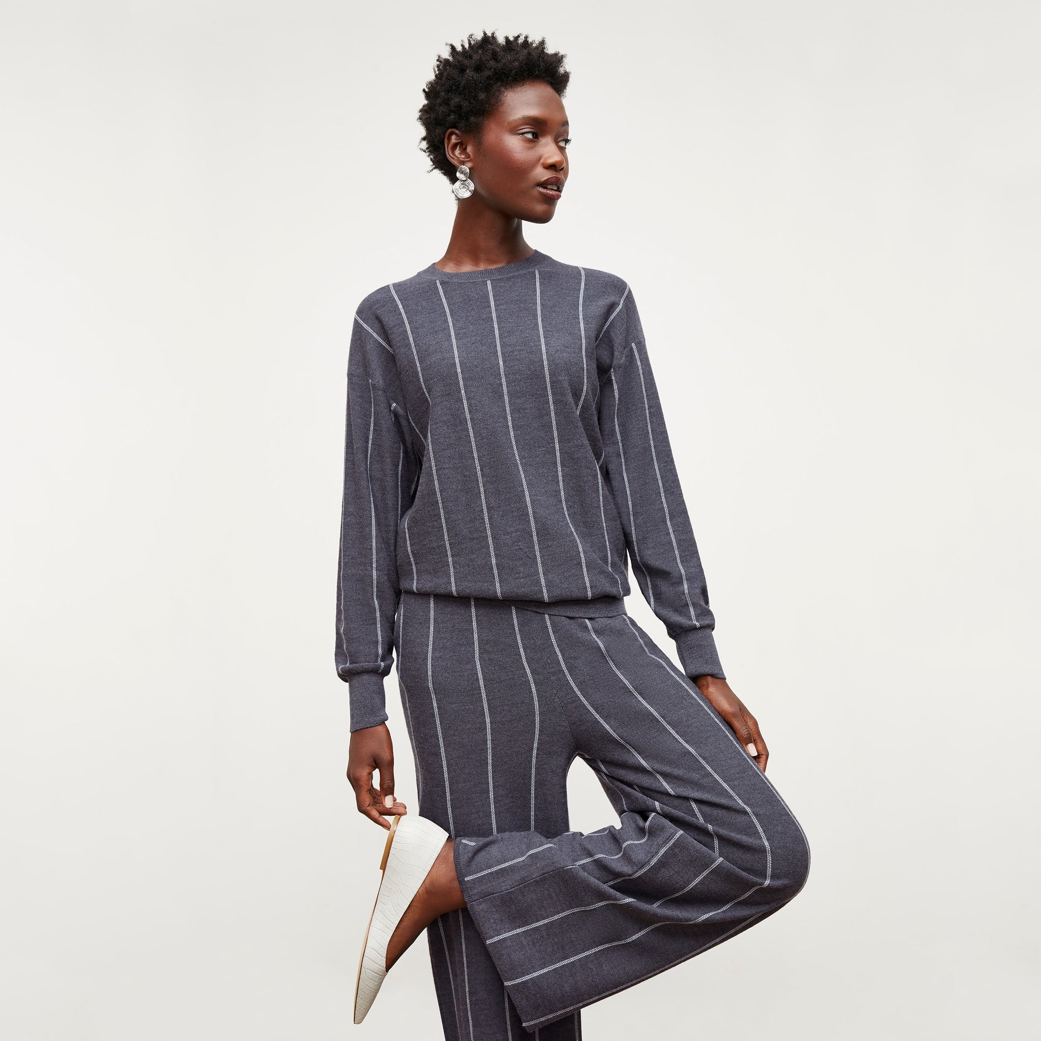 Front image of a woman standing wearing the Ingola Sweater—Braided Stripe in Charcoal / Ivory 
