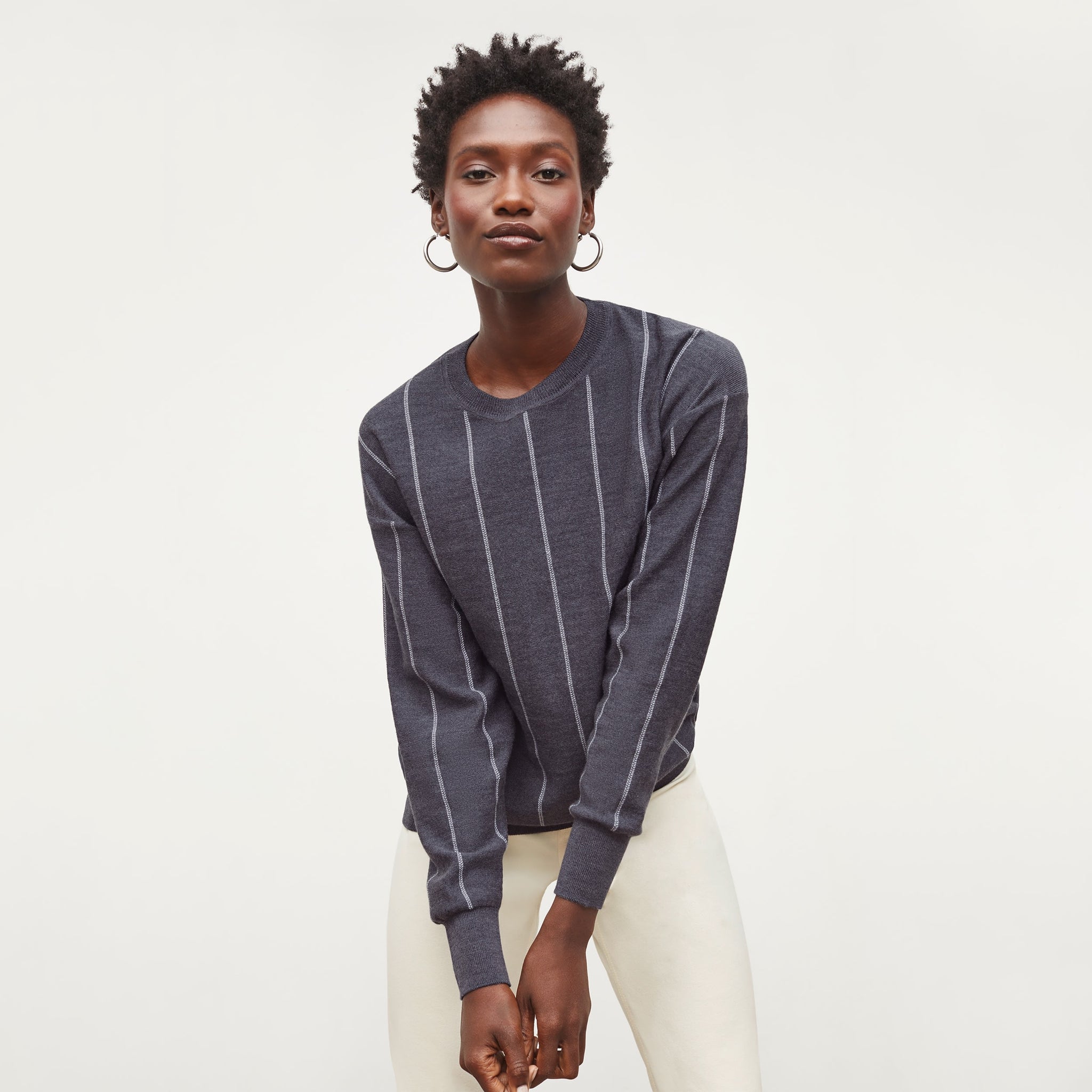 Front image of a woman standing wearing the Ingola Sweater—Braided Stripe in Charcoal / Ivory