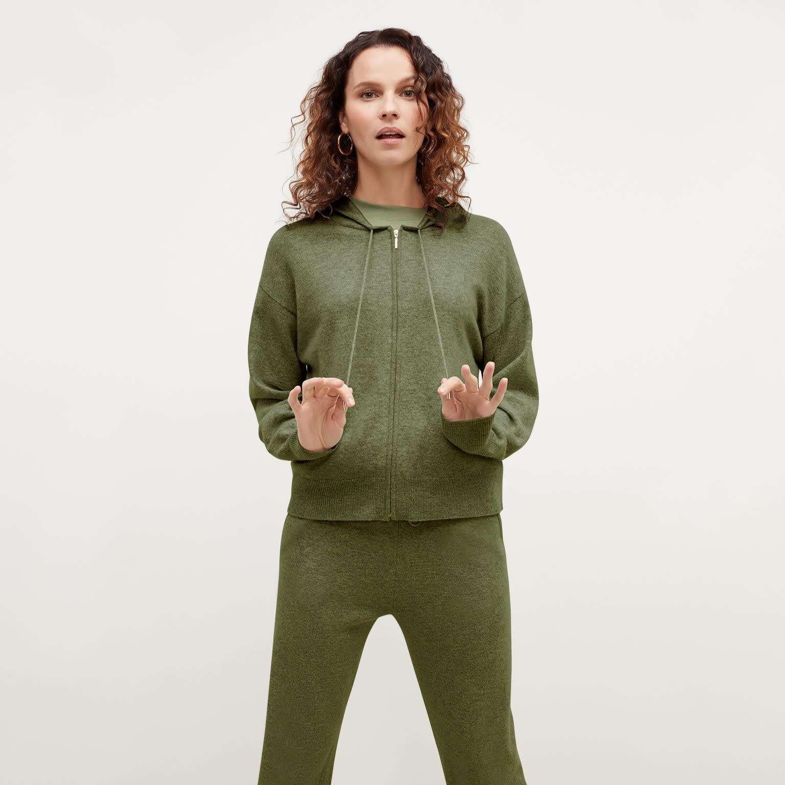 Front image of a woman standing wearing the Judith Hoodie—Cashmere in OliveBack image of a woman standing wearing the Judith Hoodie—Cashmere in Olive