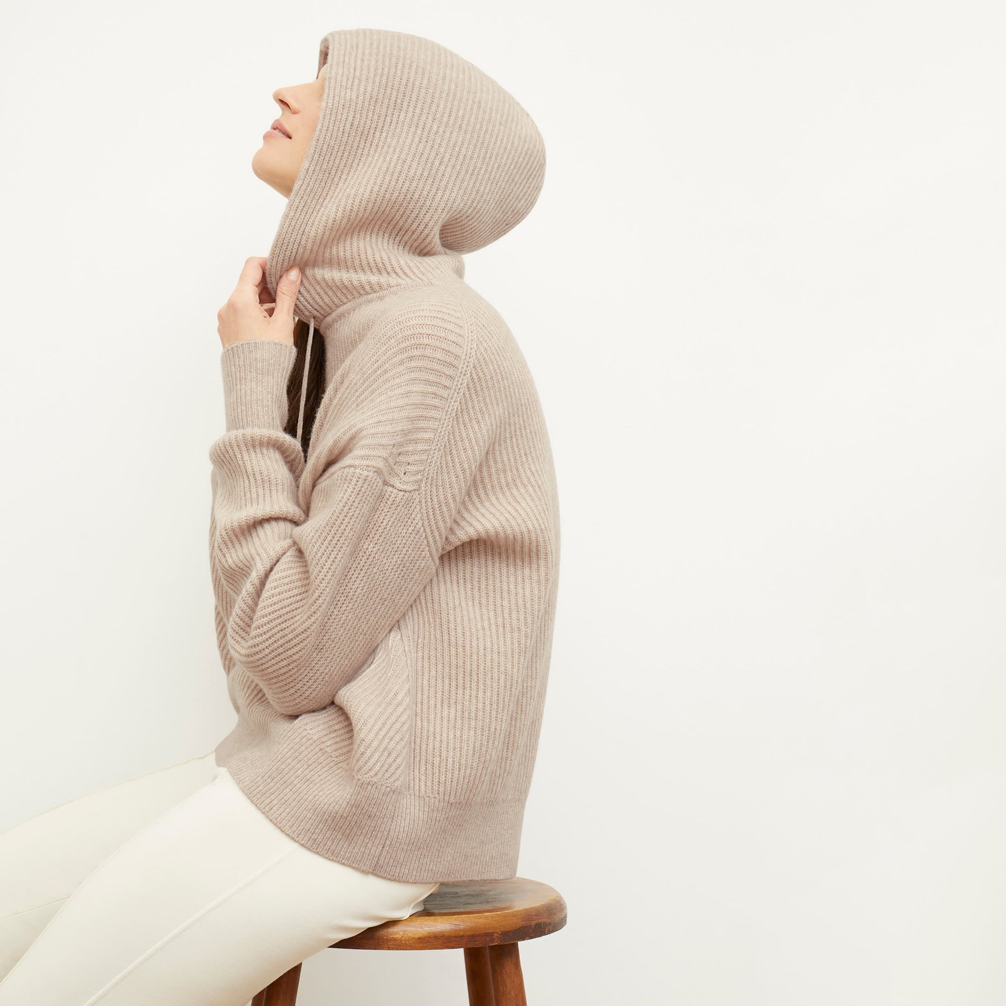 Side image of a woman standing wearing the Freya Hoodie—Cashmere/Wool in Oatmeal Melange