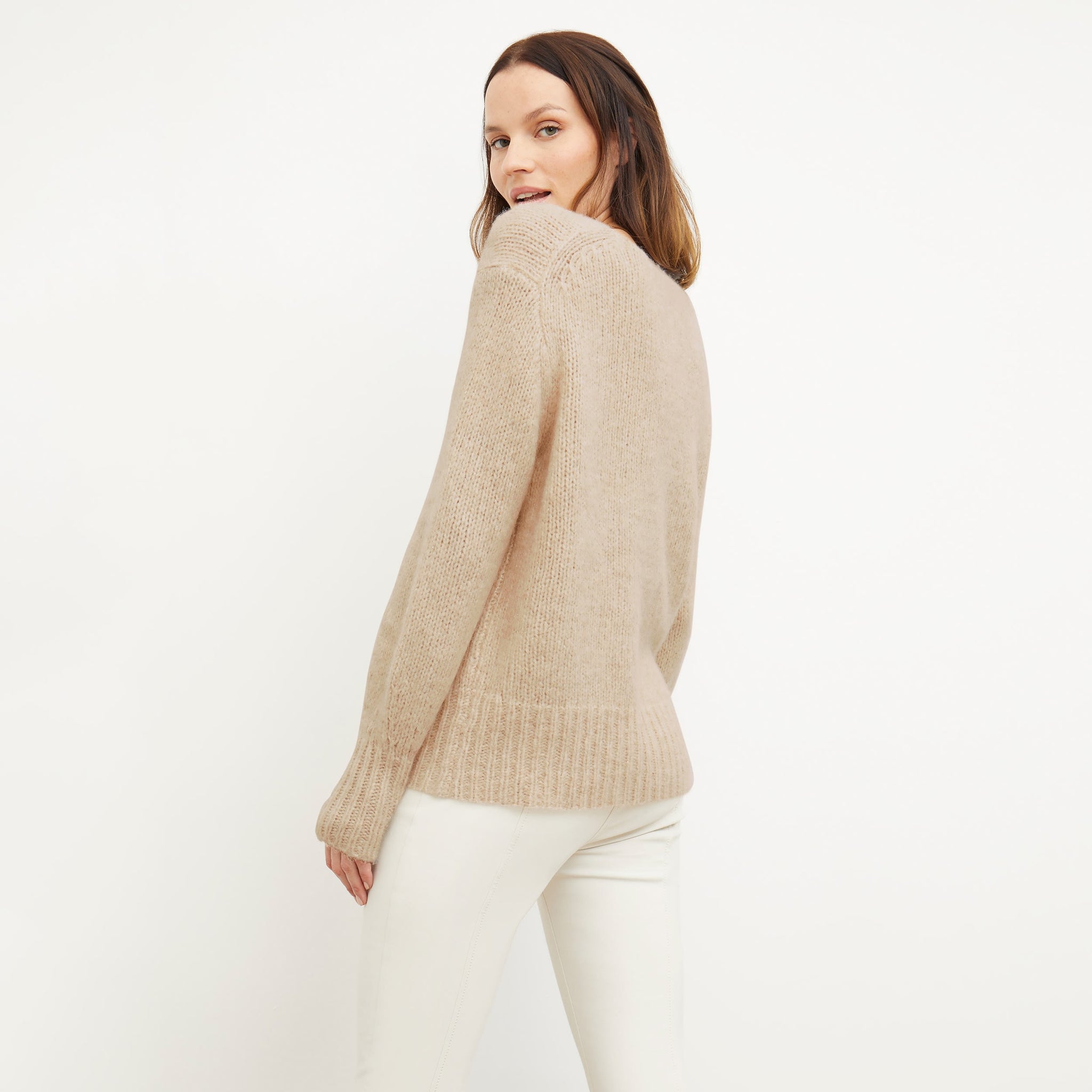 Back image of a woman standing wearing the Cathy Sweater—Glimmer Alpaca in Jasmine