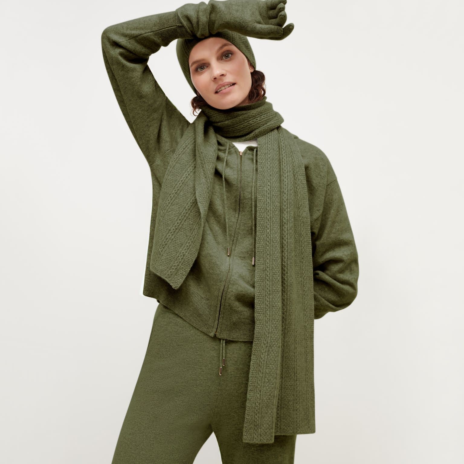 Front image of a woman standing wearing the Circle Cable Scarf—Cashmere in Olive