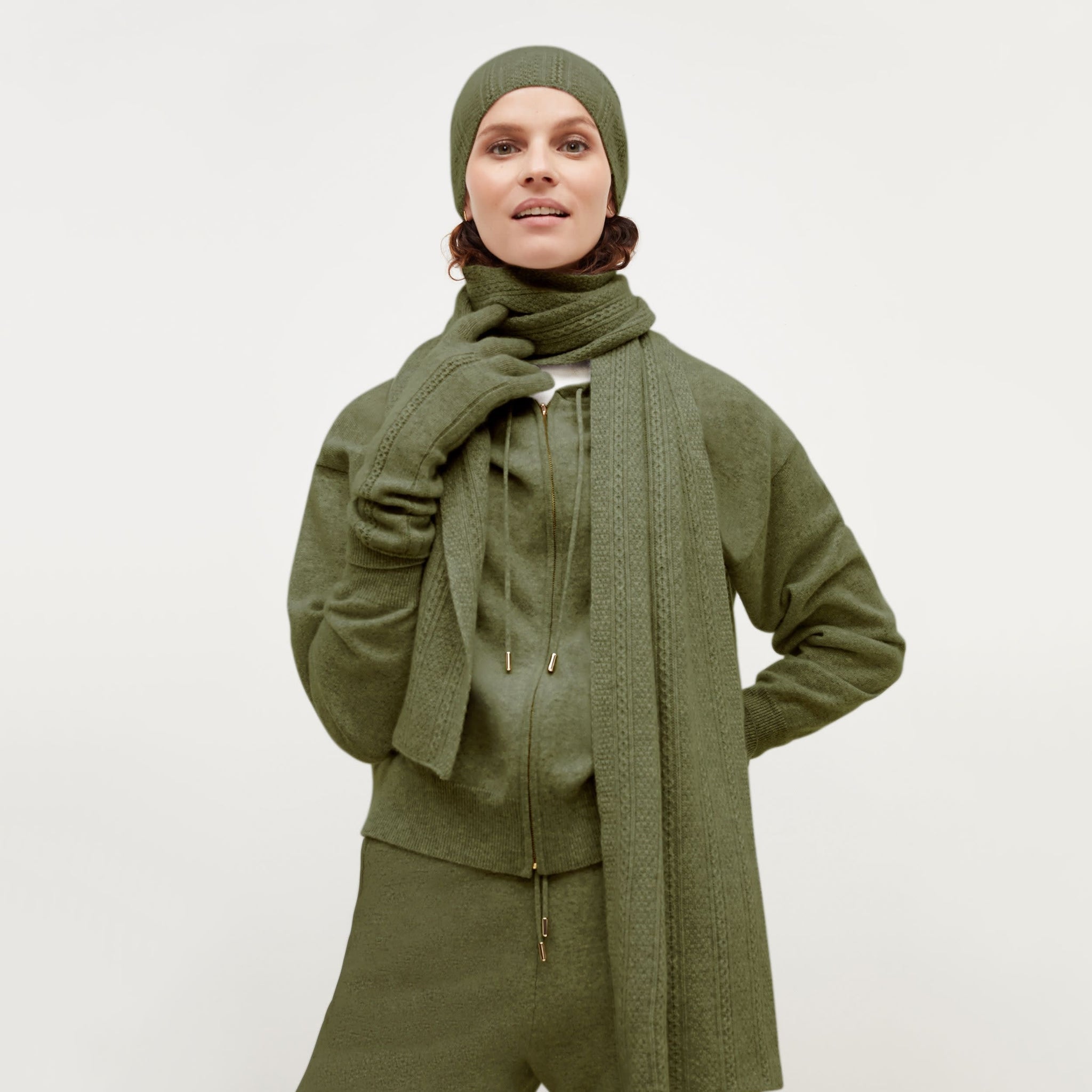 Front image of a woman standing wearing the Circle Cable Beanie—Cashmere in Olive