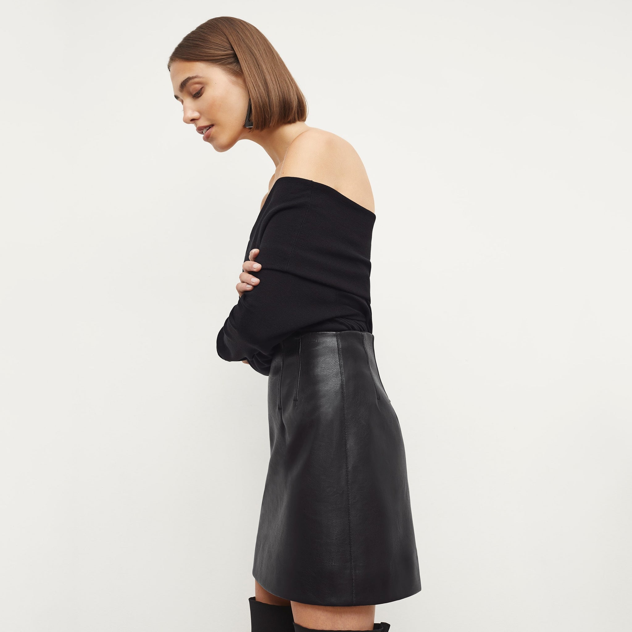 Side image of a woman standing wearing the Whitney Skit—Vegan Leather in Black